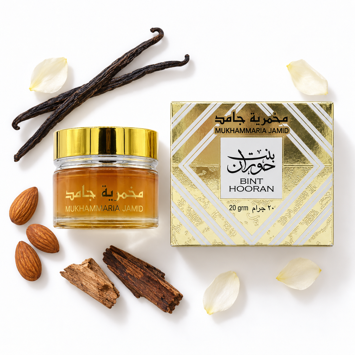 Bint Hooran Mukhammaria Jamid 20g closed gold-capped cream jar and carton on white with almonds, vanilla, pale petals and wood.